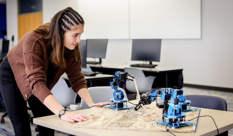 Nathalie Primbs '25 observing robotic arms in the middle of Basile Hall's Data Science computer lab